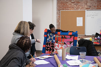 People sewing a quilt