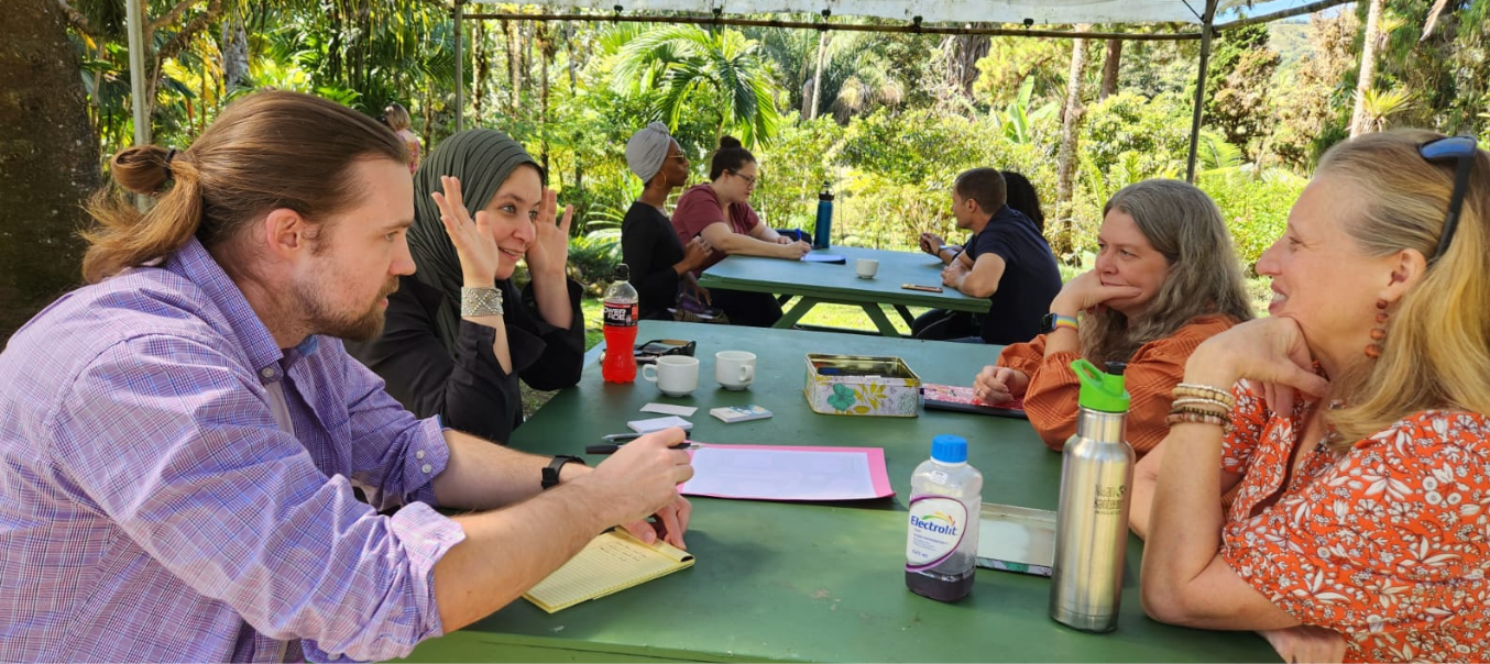 People work and talk sitting at a picnic table outside in Costa Rica