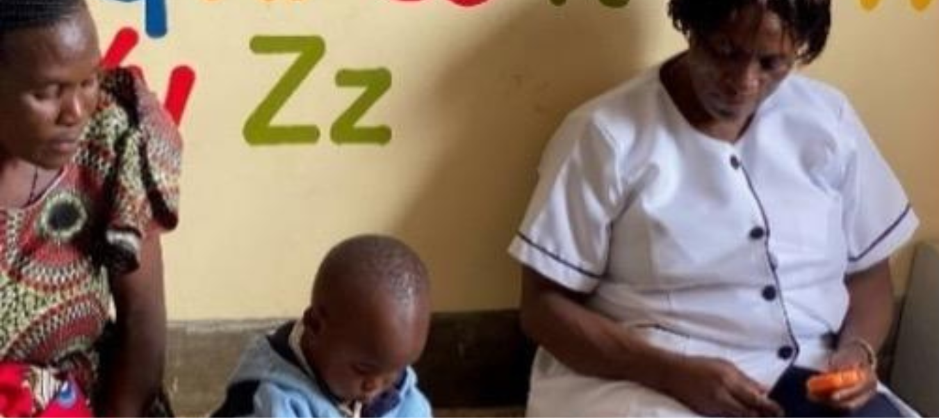 A nurse sits with a mother and child