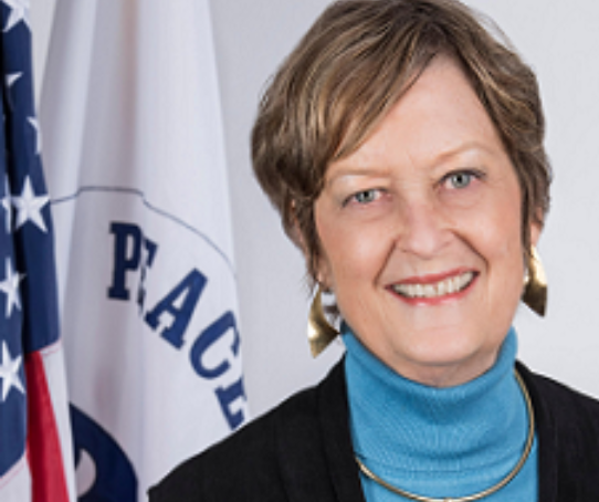 Headshot of a woman in front of a flag