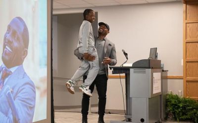 Pro Football Hall of Famer Ray Lewis holds up local youth Blair Pinnacle, re-creating a moment from 2019 when the former Raven hoisted then-second-grader Pinnacle at the groundbreaking ceremony for UMB’s Community Engagement Center on South Poppleton Street.