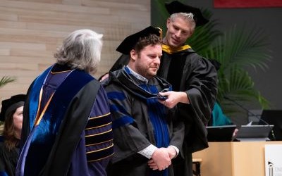 PhD graduate Todd Becker receives his hood from faculty mentor John Cagle, PhD, during the 2024 Graduate School Hooding Ceremony.